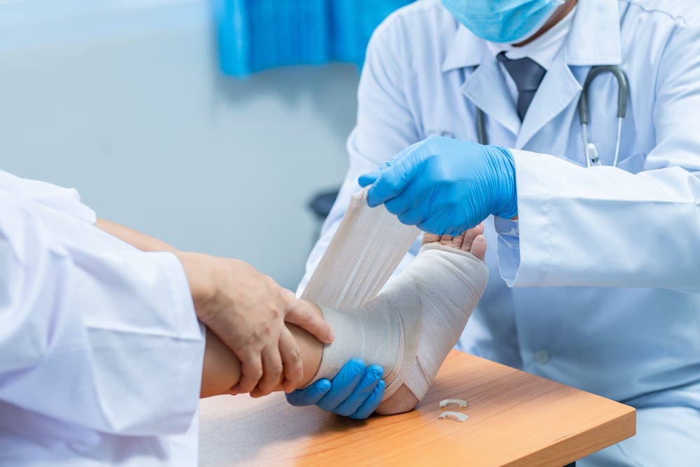 doctor wrapping a patient's ankle in a cast