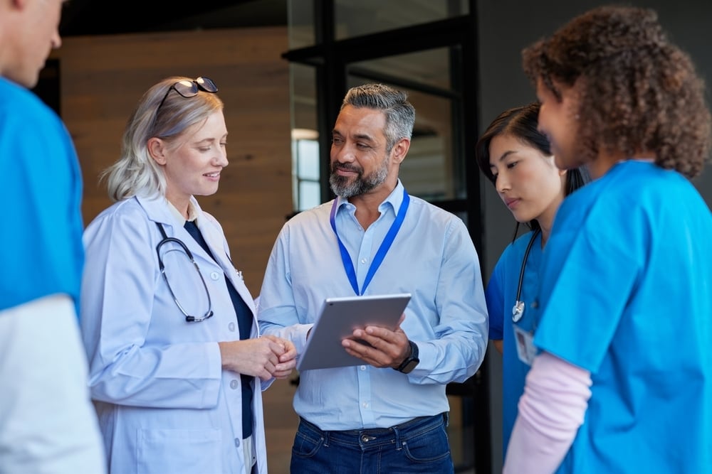 Medical mixed race team consulting with pharmaceutical representative at hospital. Healthcare hospital staff reviewing new pharmaceutical information. Doctors and nurses discussing.