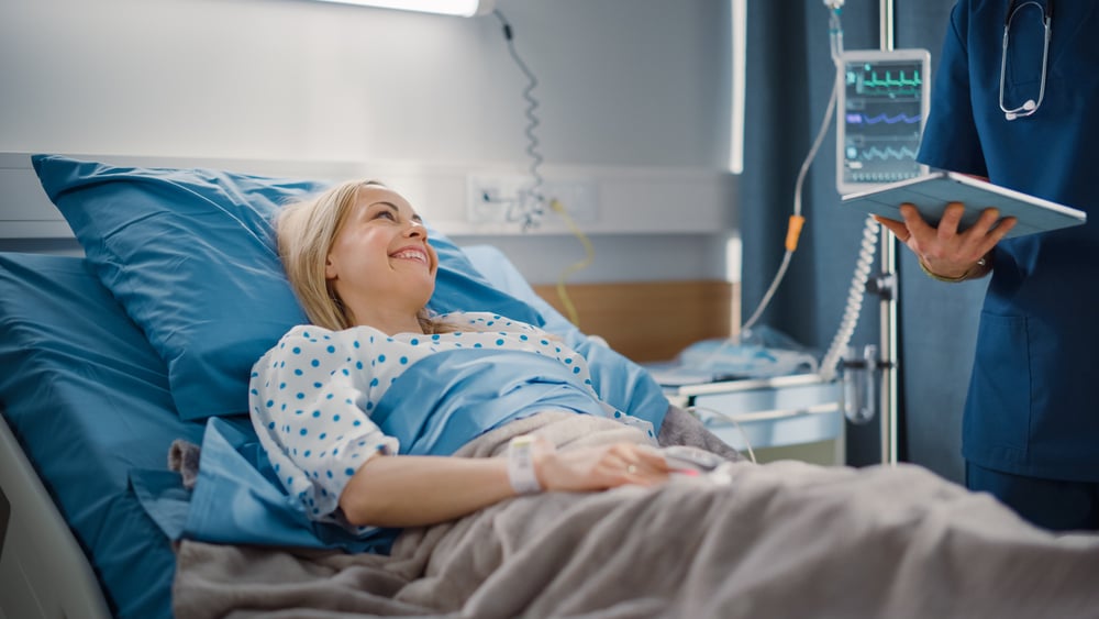 Friendly Male Nurse Talks to Female Patient Resting in Bed. Male Nurse or Physician Uses Tablet Computer, Does Checkup and HOOS JR. Survey.