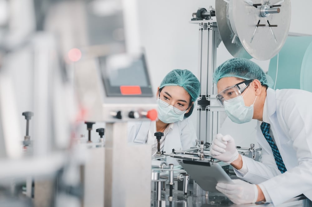 Both male and female Asian scientists are outfitted with protective gear. 