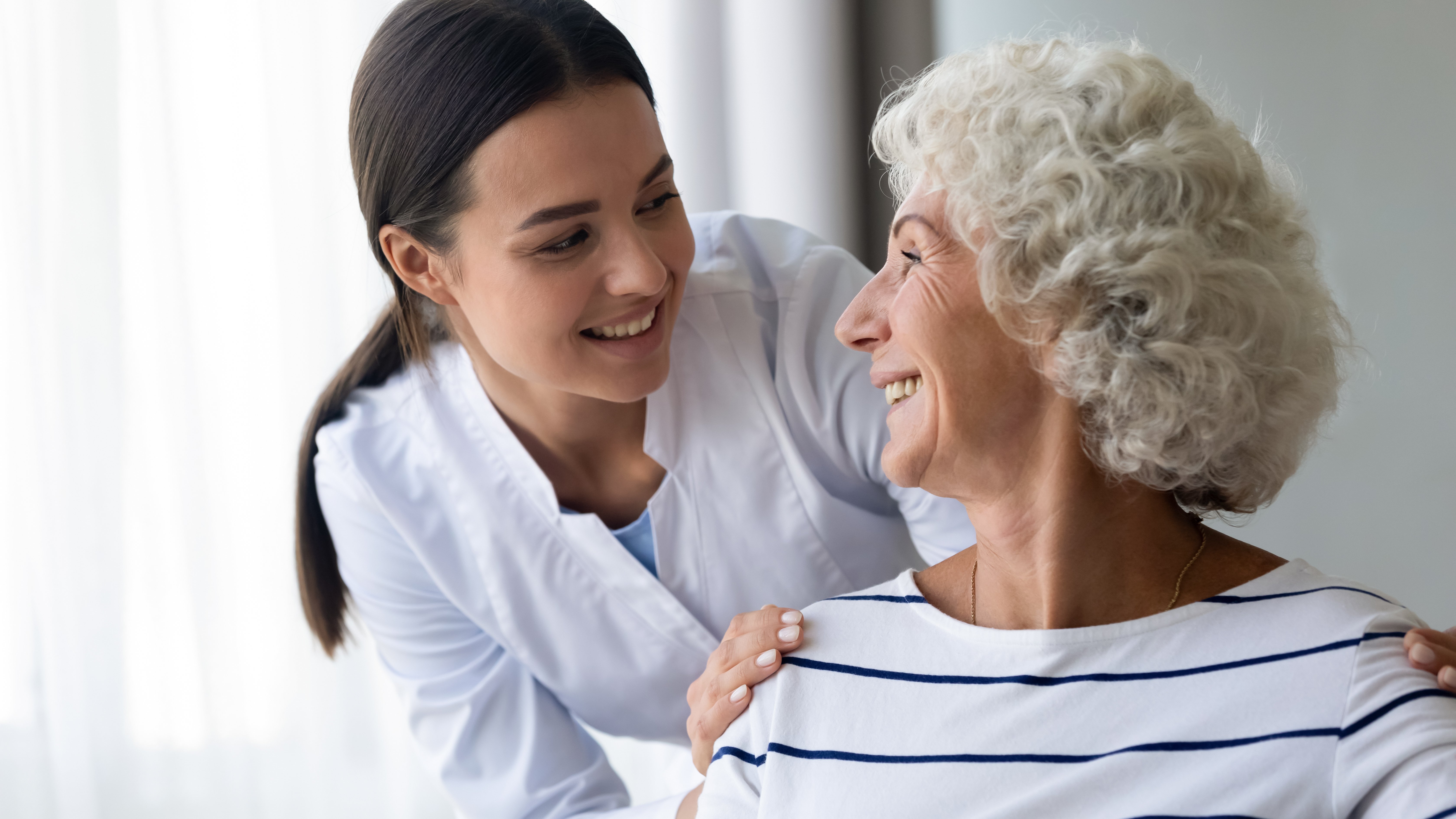 Patient and healthcare provider smiling at each other which can be linked to the fact that the patient is satisfied with the healthcare she is receiving. 